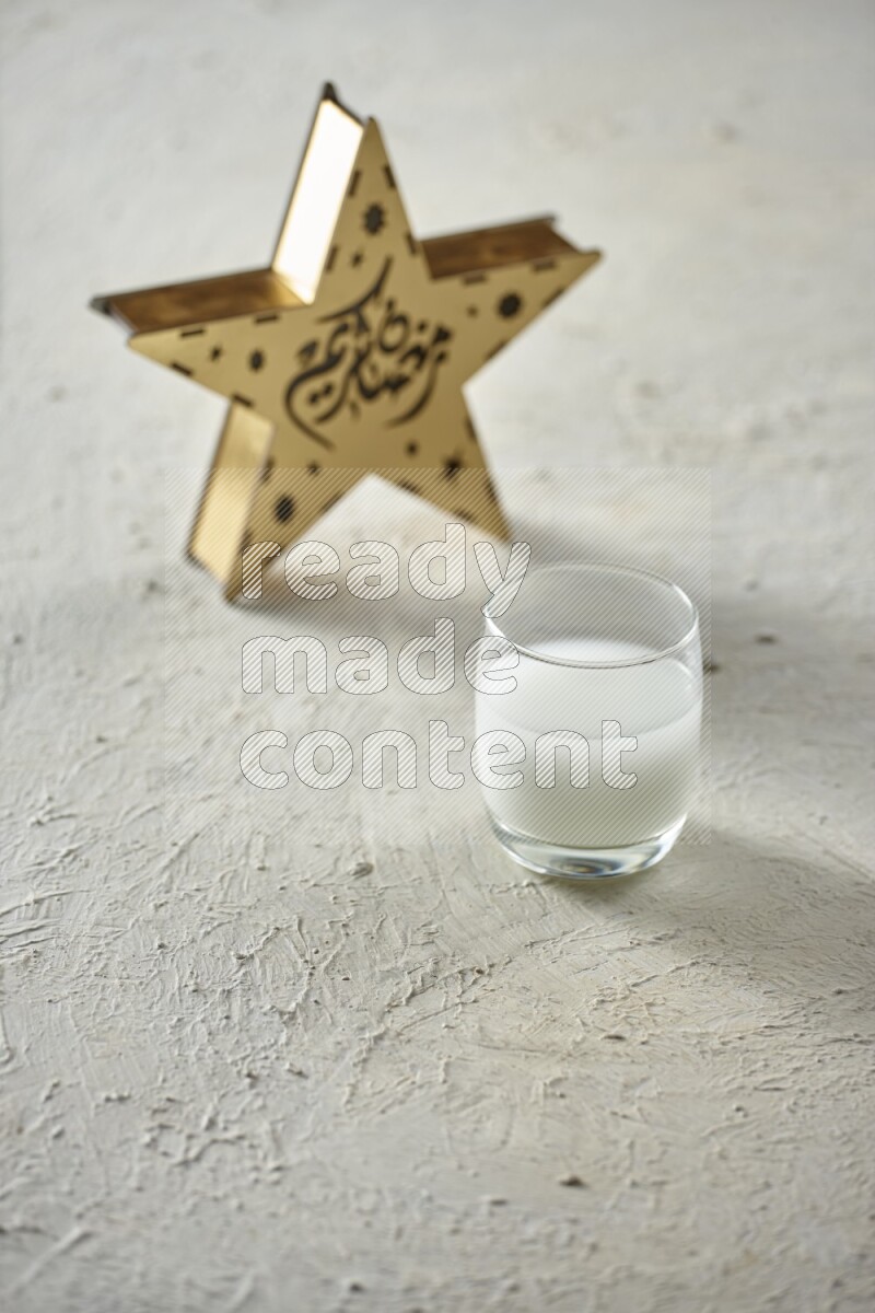 A wooden golden star lantern with different drinks, dates, nuts, prayer beads and quran on textured white background