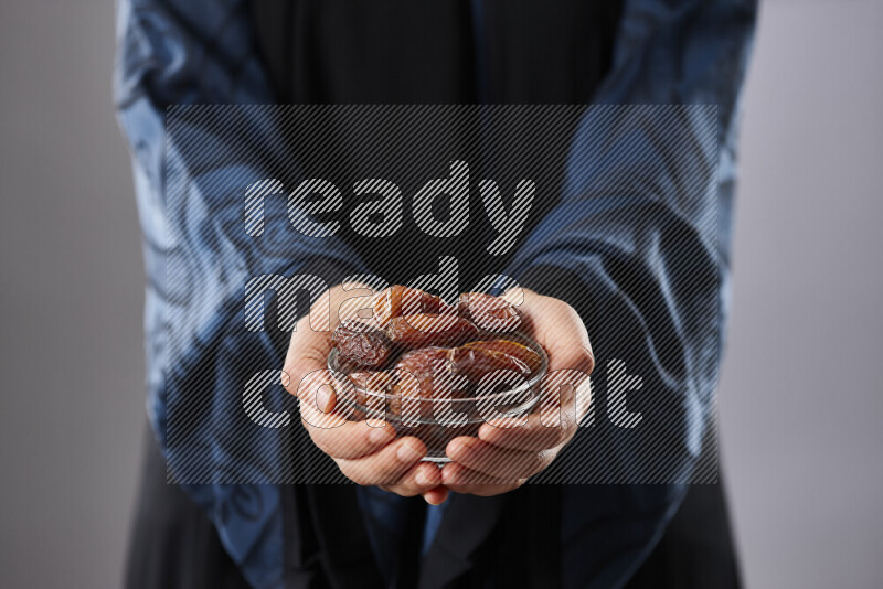 Woman in abaya holding dates in different positions