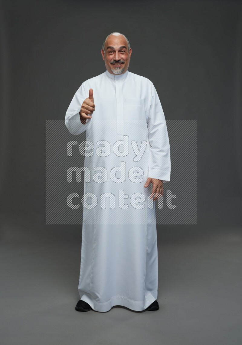 Saudi man without shomag Standing Interacting with the camera on gray background