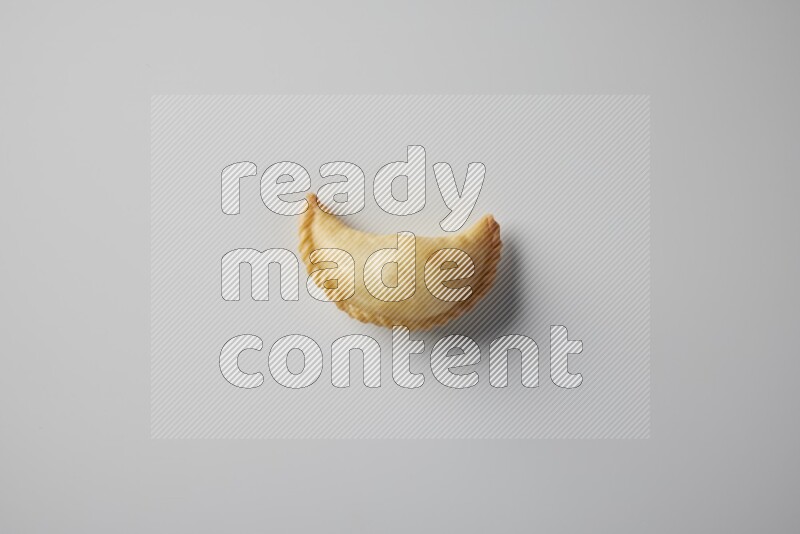 One fried sambosa from a top angle on a white background