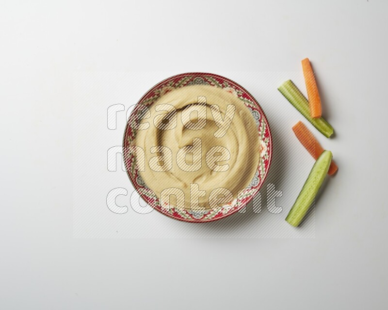 Plain Hummus in a red plate with patterns on a white background