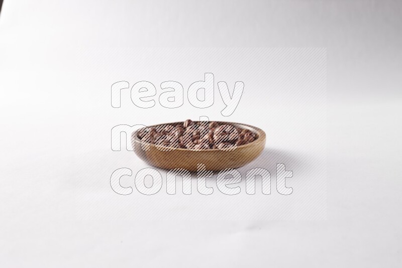 Hazelnuts in a wooden bowl on white background