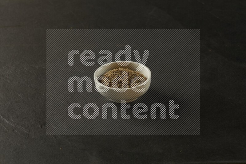 wooden round sauce bowl filled with herbs on grey textured countertop