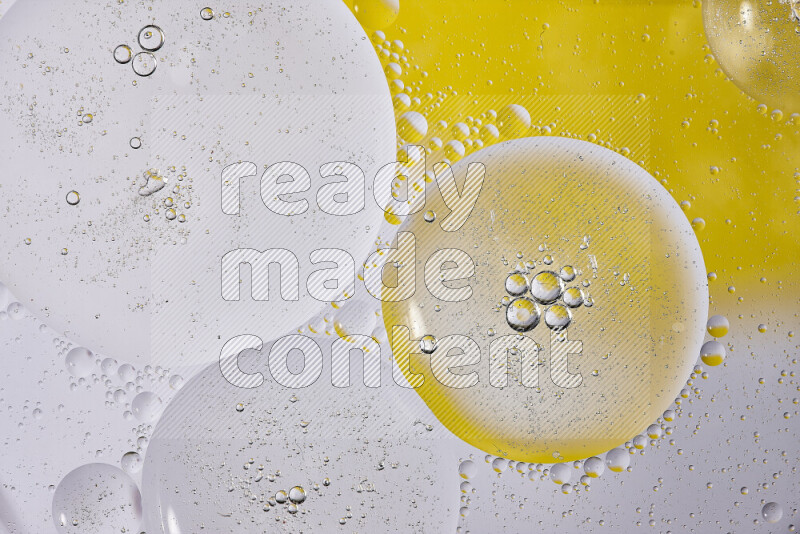 Close-ups of abstract oil bubbles on water surface in shades of white and yellow