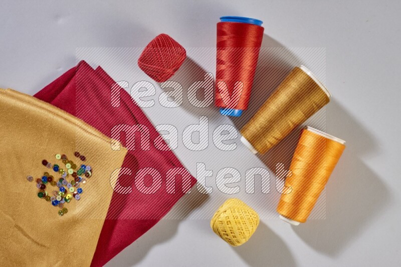 Multicolored fabrics with sewing supplies on grey background