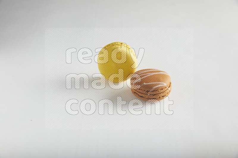 45º Shot of of two assorted Brown Irish Cream, and Yellow Lemon macarons on white background