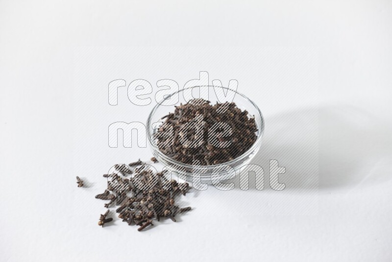 A glass bowl full of cloves on a white flooring