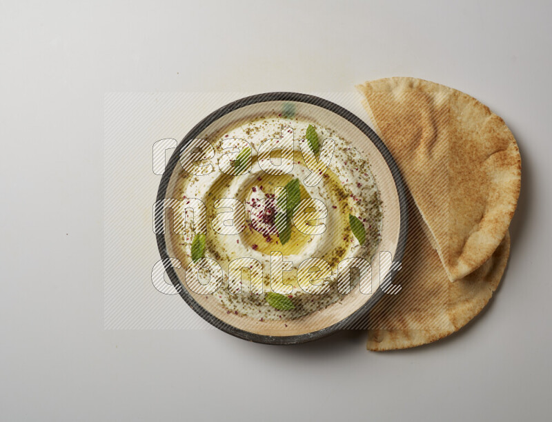 Lebnah garnished with zaater, mint & sumak in a pottery plate on a white background