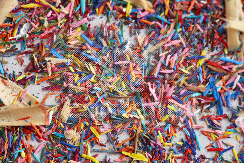 This image showcases a vibrant multicolored pencil shavings scattered on grey background