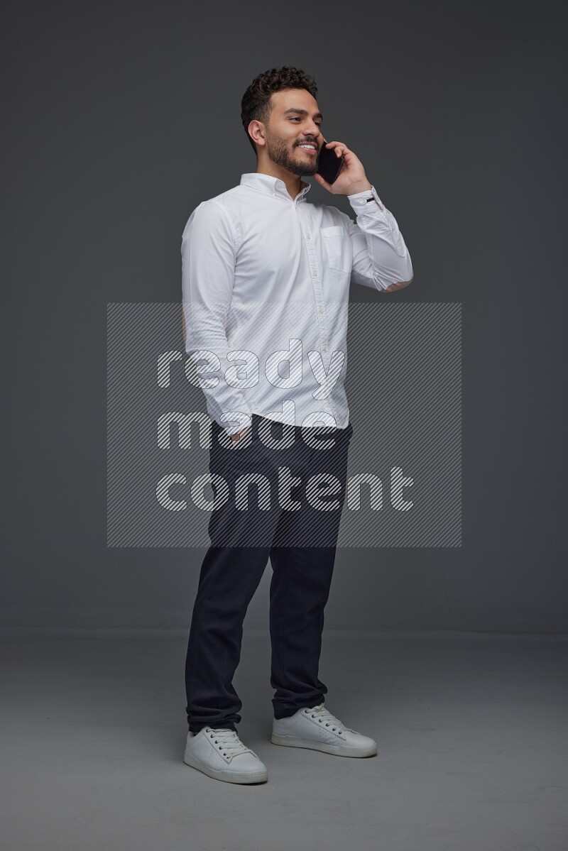 A man wearing smart casual talking in the phone eye level on a gray background