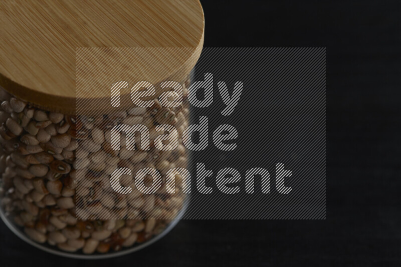 Black-eyed peas in a glass jar on black background