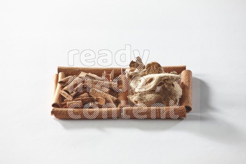 2 squares of cinnamon sticks full of cinnamon and dried ginger on white flooring