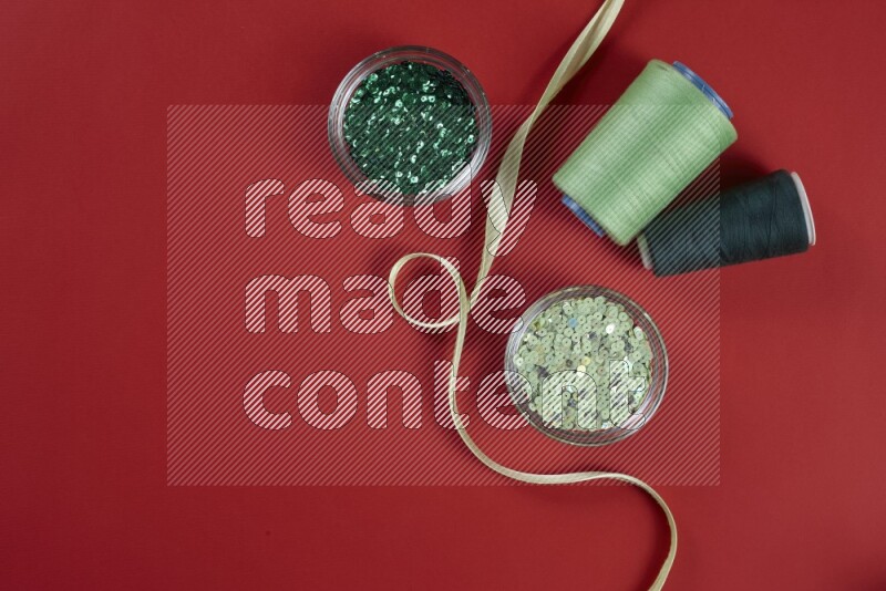 A green and red collection of sewing and tailoring tools arranged on a red background