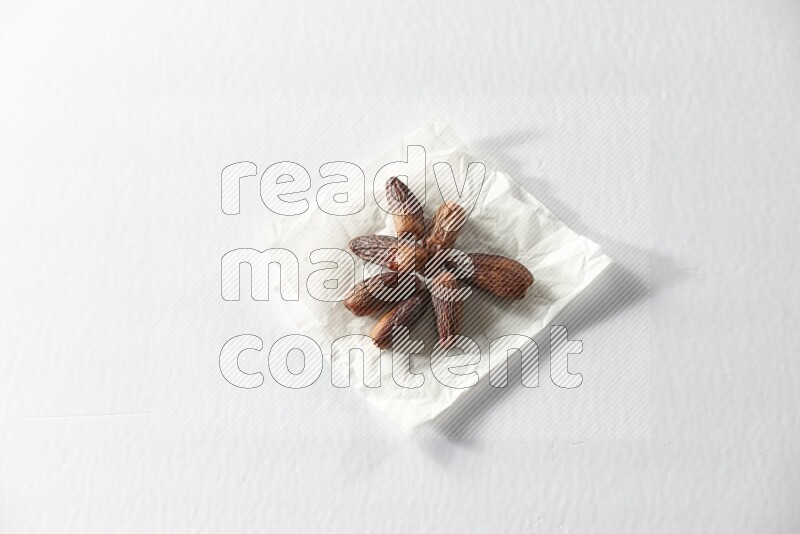 Dried dates on a crumpled piece of paper on a white background in different angles