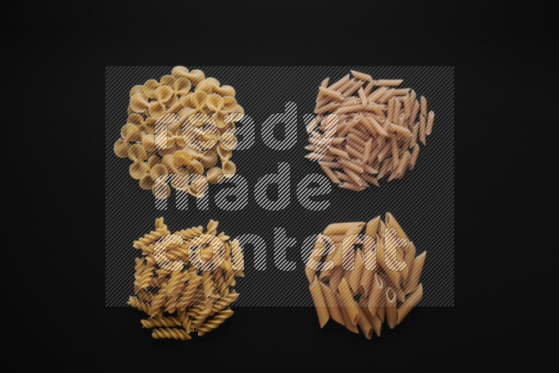 Different pasta types in bunches on black background