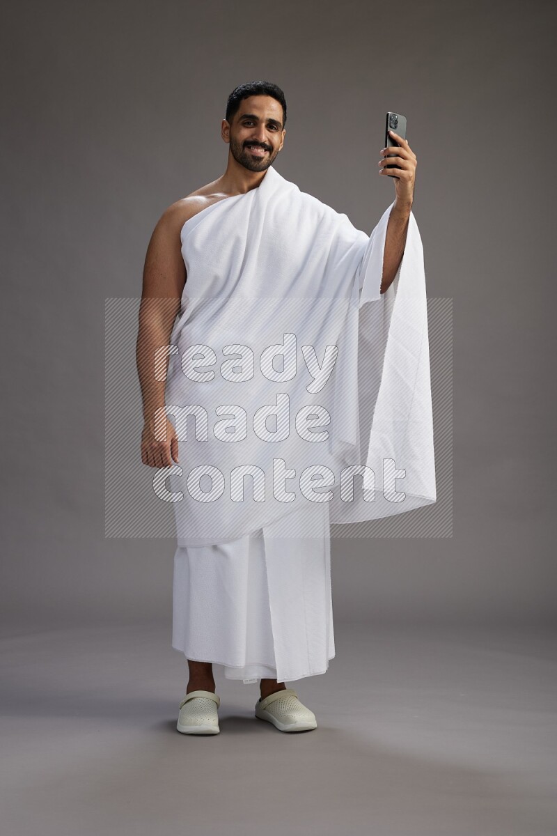 A man wearing Ehram Standing taking selfie on gray background