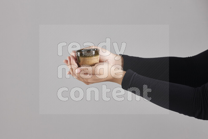 A woman in black abaya holding different pottery essentials in different positions