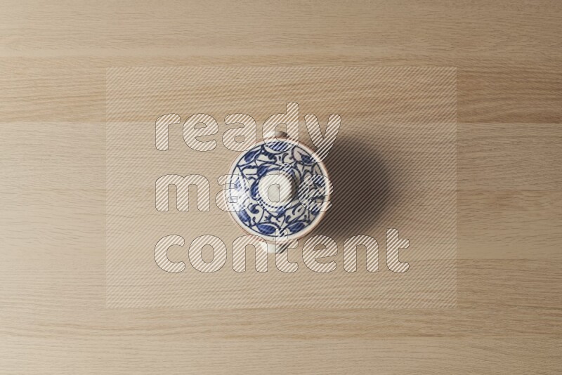 A multicolored pottery pot on light wooden background