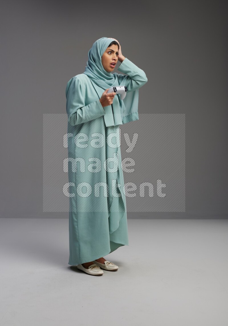 Saudi Woman wearing Abaya standing Playing Games on Gray background