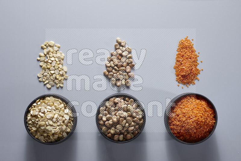 Legumes in pottery bowls on light grey background