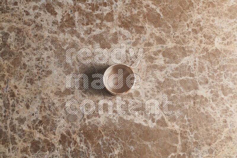 A multicolored pottery bowl on beige marble background