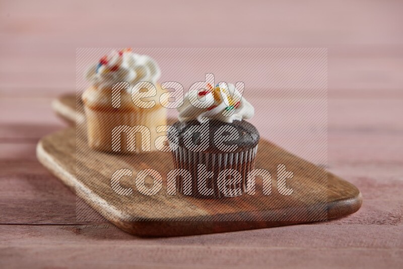 Chocolate mini cupcake topped with cream on a wooden board