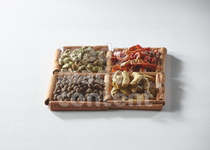 4 squares of cinnamon sticks full of dried red chilis, cardamom, turmeric fingers and allspice on white flooring
