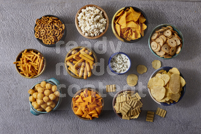 Assorted snacks in pottery bowls on grey background