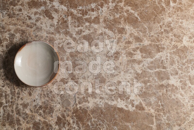 A multicolored pottery bowl on beige marble background