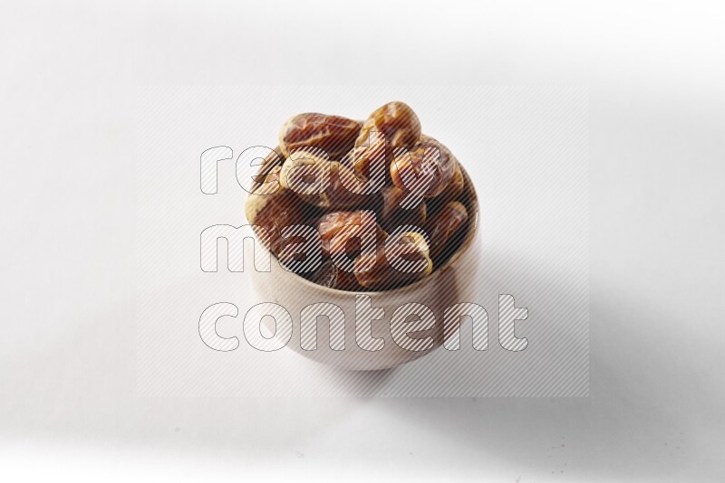 Dates in a beige pottery bowl on white background