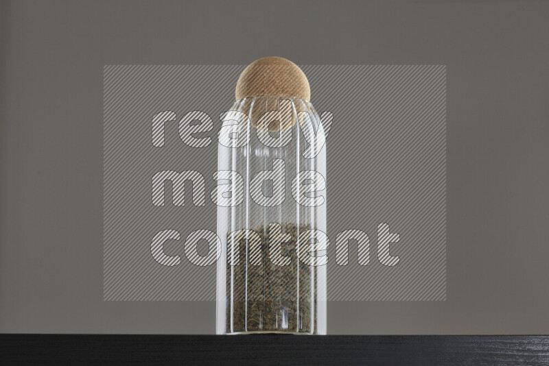Dried basil in a glass jar on black background