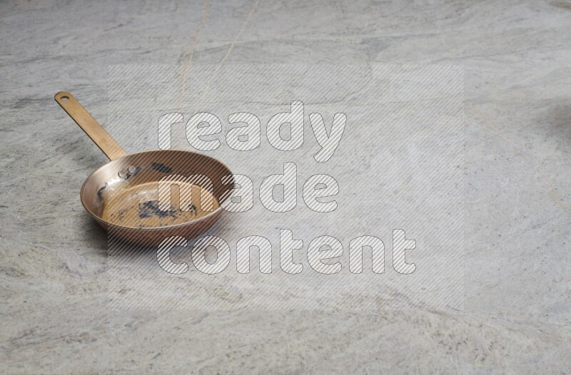 A small copper pan on grey marble background