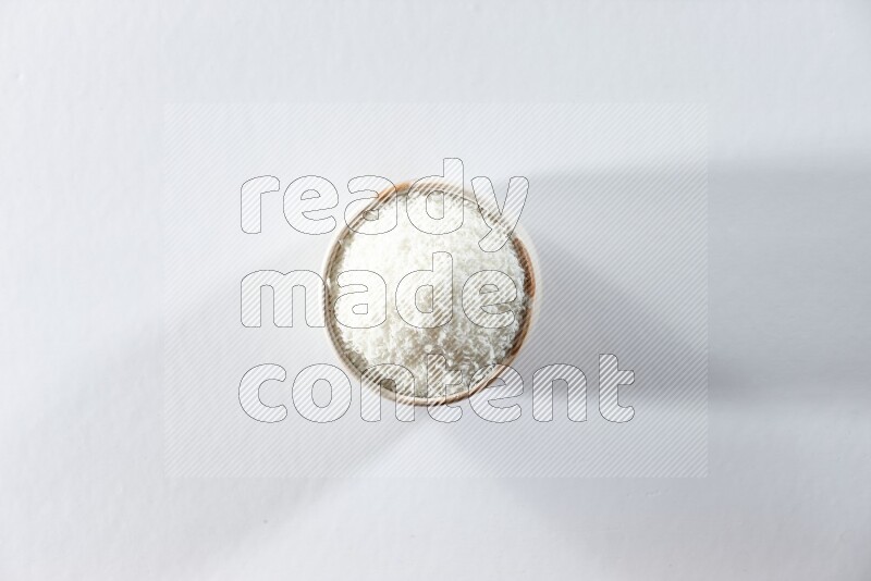 A beige ceramic bowl full of desiccated coconut on a white background in different angles