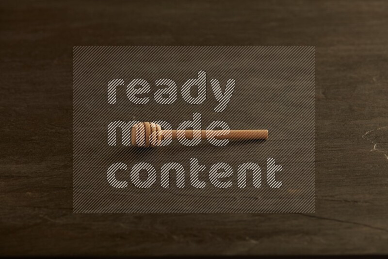 Wooden honey dipper on black slate background