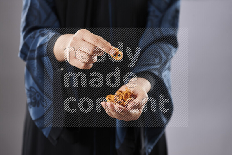 Woman in abaya holding different kinds of snacks in different positions