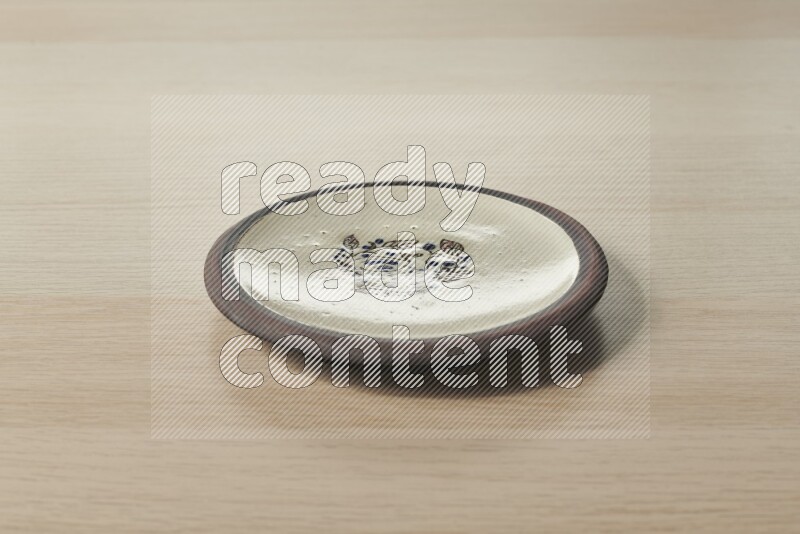 A decorative pottery plate on light wooden background
