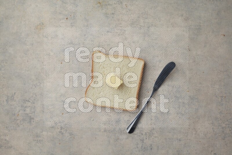 White toast slices with a butter cube and a spreading knife on a light blue textured background