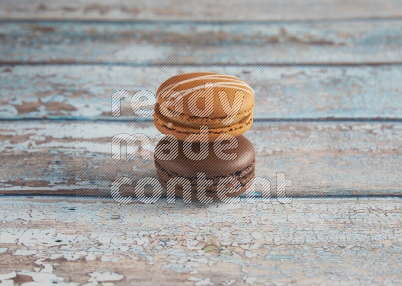 45º Shot of of two assorted Brown Irish Cream, and Brown Dark Chocolate macarons on light blue background