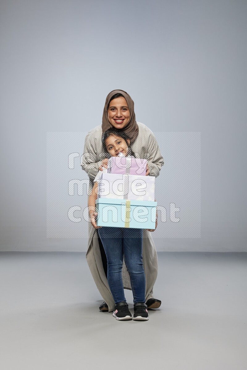A girl giving a gift to her mother on gray background