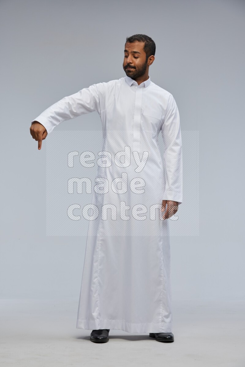 Saudi man Wearing Thob standing interacting with the camera on Gray background