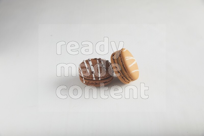 45º Shot of of two assorted Brown Irish Cream, and Brown white Chocolate Caramel macarons on white background