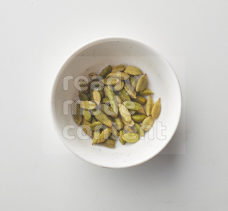 Top-view shot of Cardamon in a container on white background