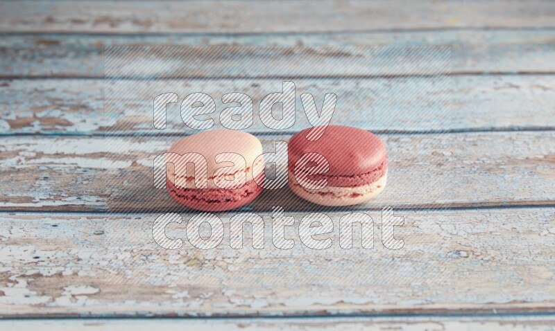 45º Shot of two Pink Litchi Raspberry macarons on light blue wooden background