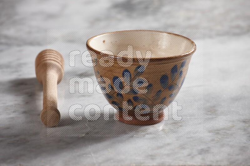 Decorative pottery bowl with wooden honey dipper on the side on grey marble background