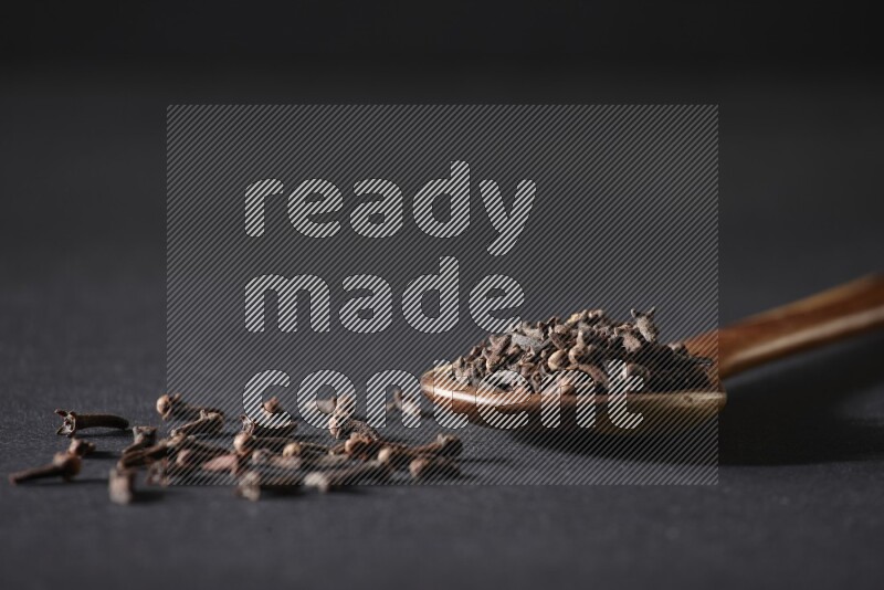 حبوب القرنفل في ملعقة خشبية علي خلفية سوداء