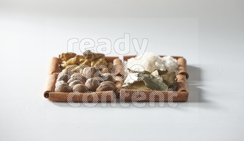 4 squares of cinnamon sticks full of salt, bay laurel, nutmeg, turmeric on white flooring