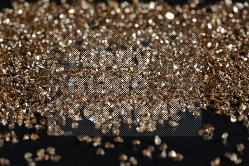 Gold shimmering fragments of glass scattered on a black background