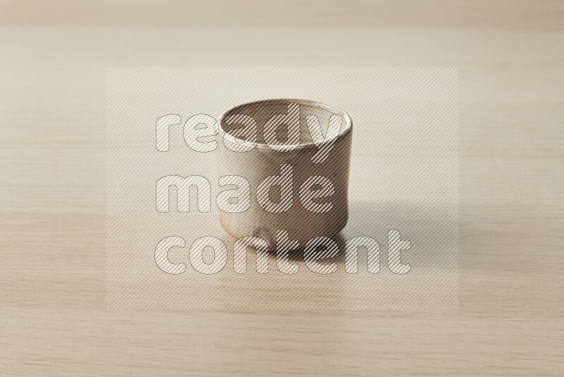 A pottery cup on light wooden background