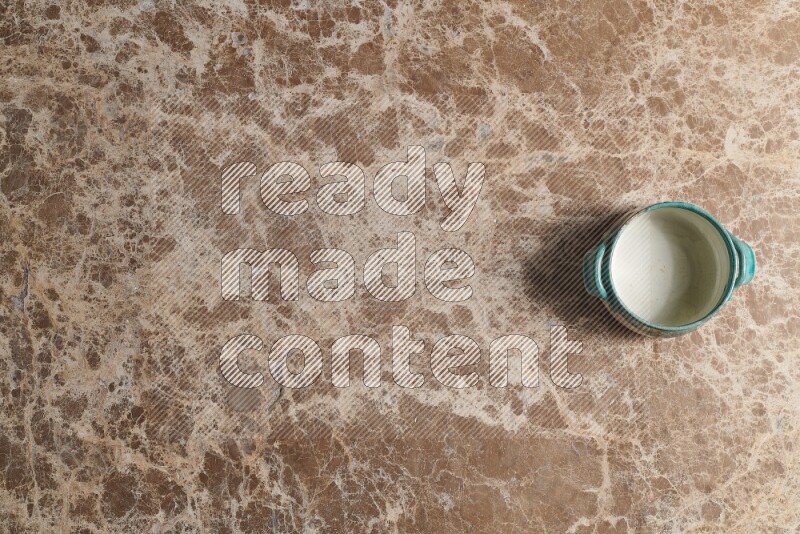 A multicolored pottery bowl on beige marble background