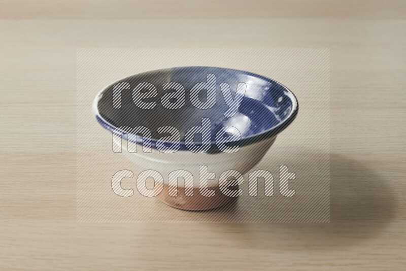 A multicolored pottery bowl on light wooden background